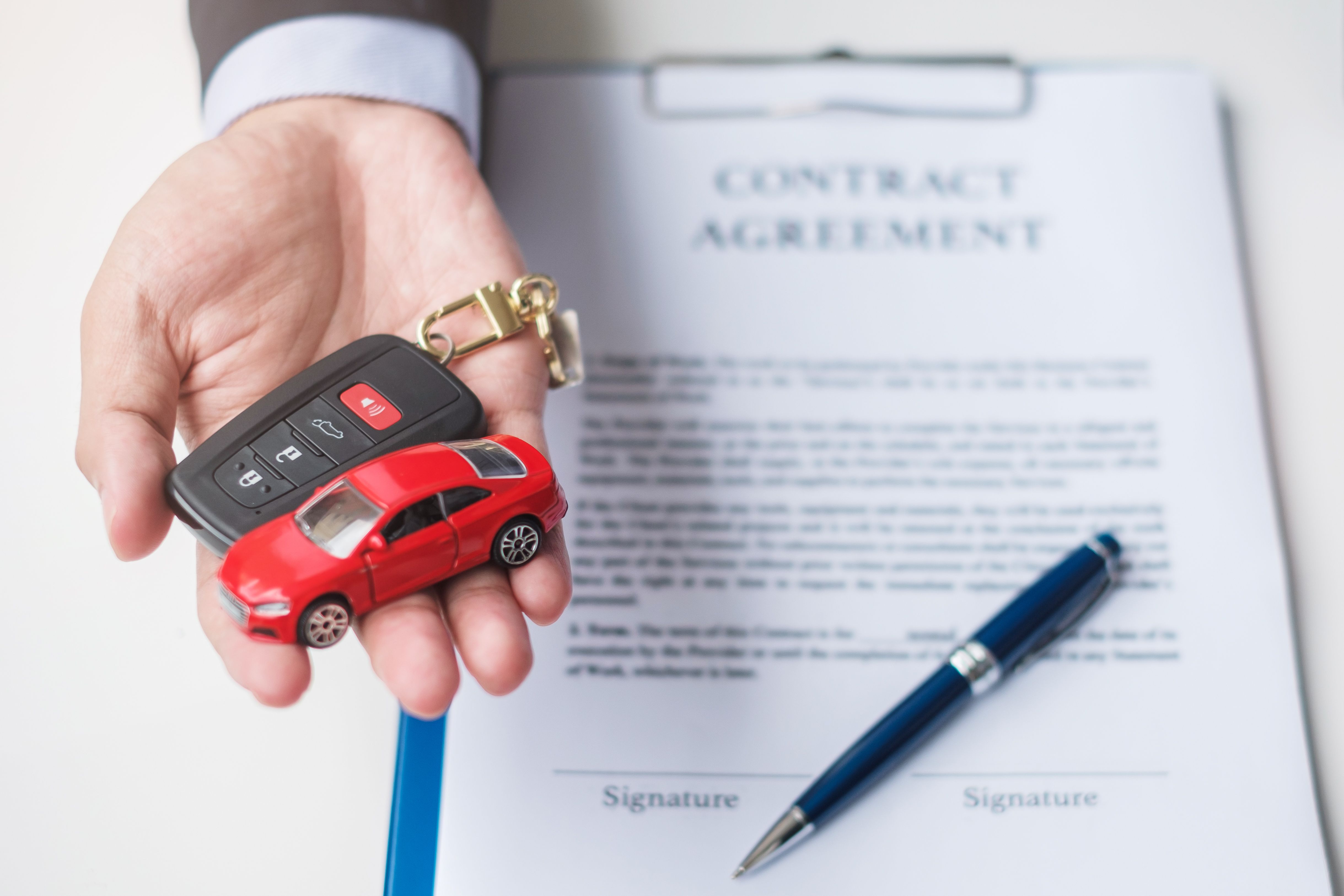 businessman-hand-holding-red-car-toy-with-vehicle-keyless-pen-contract-document-buy-sale-insurance-rental-contract-agreement-concepts.jpg