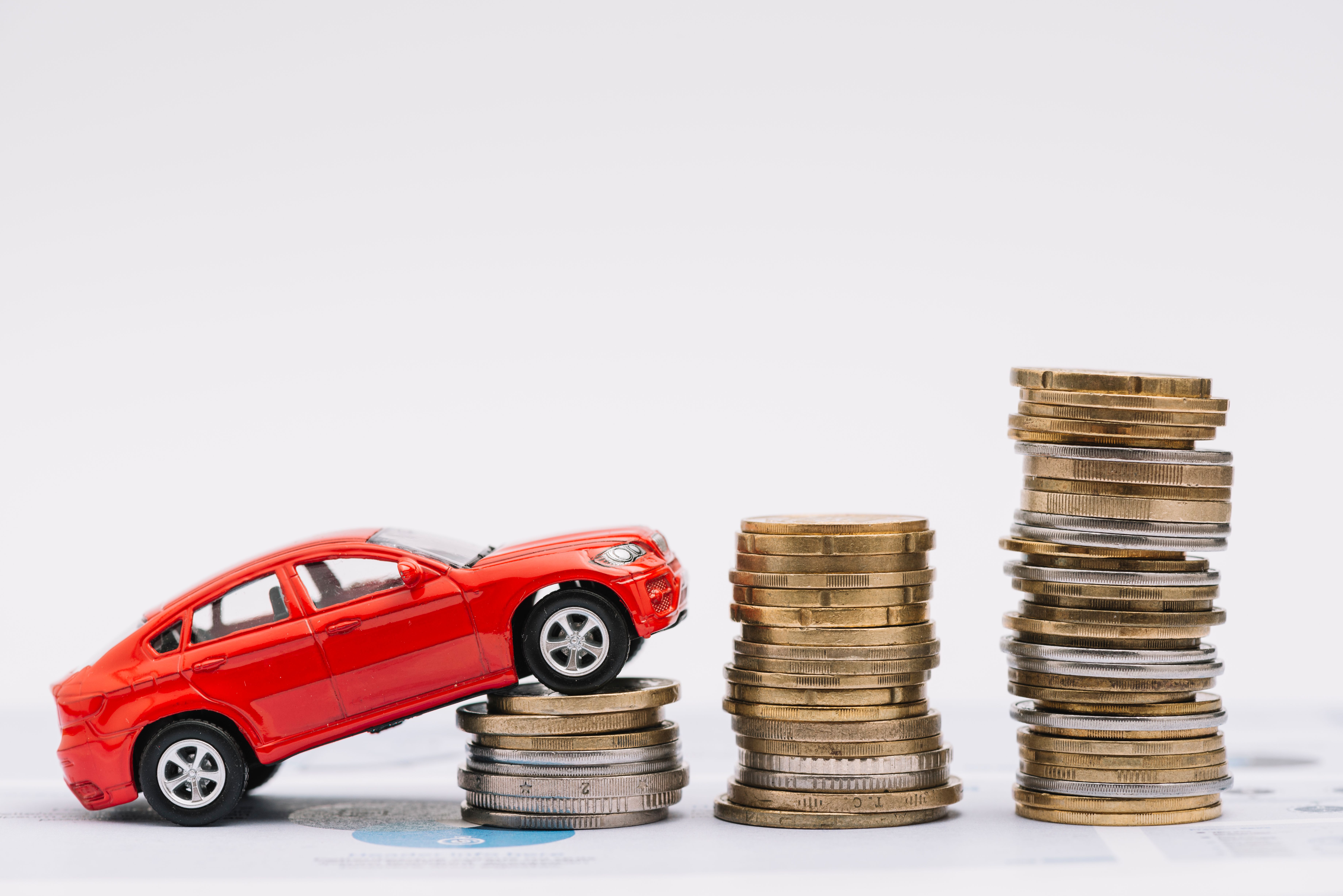 toy-car-going-up-increasing-stack-coins-against-white-background.jpg